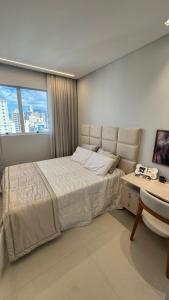 Apt luxo vista mar 160m com jacuzzi e 2 garagens في ايتابيما: غرفة نوم بها سرير ومكتب ونافذة