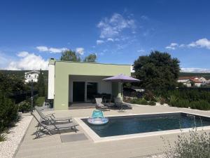 a swimming pool with two chairs and an umbrella at Villa Ispo Volta in Posedarje