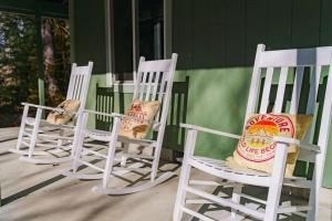 3 chaises à bascule blanches assises sur une terrasse couverte dans l'établissement Chateau Relaxeau Game Room Hot Tub Fire Pit, à Mount Hood Village 59 autres photos