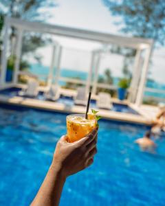 a person holding a drink in front of a pool at Greco Hotel in Búzios