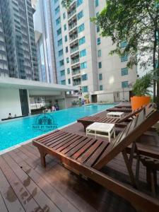 a swimming pool with a wooden deck with a table and benches at Mercu Summer Comfort Luxe Suites By KLCC in Kuala Lumpur