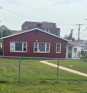 a red house with a fence in front of it at 3 bedroom near O'Hare Airport- King bed 1 Story in River Grove