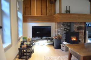 a living room with a fireplace and a flat screen tv at Vakantiehuis de Bakspieker in Haaksbergen