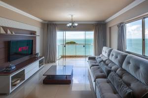 a living room with a large couch and a television at IPTZ170- Frente mar c/ vista incrível do 17º andar in Balneário Camboriú