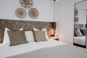 a bedroom with a white bed with pillows and a mirror at Hotel Kodde in Aagtekerke +57 photos