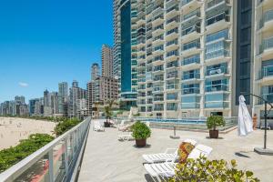 a balcony with chairs and a beach and buildings at IPTZ170- Frente mar c/ vista incrível do 17º andar in Balneário Camboriú