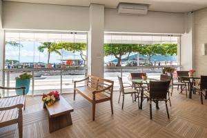 a dining room with tables and chairs and a view of the beach at IPTZ170- Frente mar c/ vista incrível do 17º andar in Balneário Camboriú