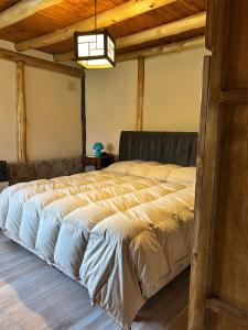 Cabañas del Pasaje في Las Compuertas: سرير كبير في غرفة ذات سقف خشبي