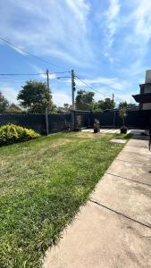 a grassy yard with a fence and a sidewalk at Eliseo Chalet in Yerba Buena