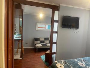 Un dormitorio con un televisor en la pared y un sofá. en Foresta Urban Suites, en Santiago