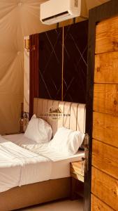 Una cama con sábanas blancas y almohadas en una habitación. en Sadem Wadi Rum, en Wadi Rum