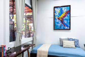 a bedroom with a colorful bird painting on the wall at El Deseo Serendipity Tortuguero in Tortuguero