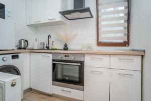 a kitchen with white cabinets and a stove top oven at Airport Connection in Iaşi +1 photo