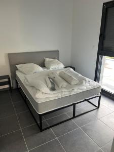 a bed with white sheets and pillows on it at Ampuis centre - Appartement indépendant in Ampuis