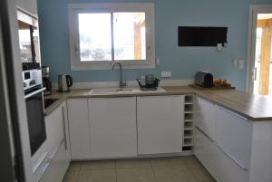 a kitchen with white cabinets and a sink and a window at Maison Océan Moliets in Moliets-et-Maa