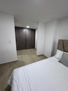 a bedroom with a white bed and a wooden cabinet at Tu Refugio en Circasia in Circasia