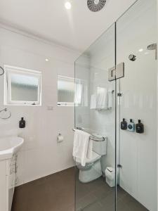 a white bathroom with a toilet and a sink at Charming 1 bedroom, park adjacent. city 5 minutes in Sydney