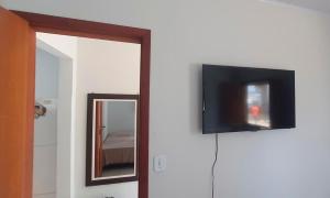a flat screen tv on a wall next to a mirror at Flat Kactus in Itacaré