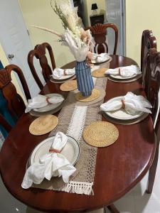 a wooden table with plates and a vase of flowers on it at Eastern Breeze in Hainamosa +6 photos