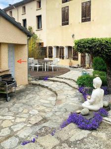 a stone patio with a statue in front of a building at Le jardin du Griffoul in Nébias