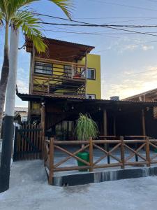 a house with a fence and a palm tree at 14 Bis Hospedagem in Arembepe