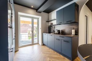 a kitchen with blue cabinets and a large window at Prisma - Univers du jeux in Chagny