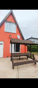 uma mesa de piquenique de madeira em frente a uma casa vermelha em Colibríes Dorados em Mar del Plata