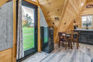 Una cocina y un comedor en una cabaña de troncos con una gran ventana en 5 Mi to Wine Trails Finger Lakes Tiny Home, en Ovid