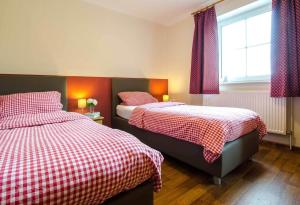 a bedroom with two beds with red and white checks at Ferienhof-Kirschenholz in Schillsdorf