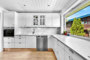 Una cocina con gabinetes blancos y una ventana grande. en House in Rotnes, Nittedal, en Nittedal