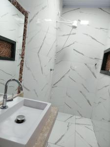 ein Bad mit einem Waschbecken und weißen Marmorwänden in der Unterkunft Casa refúgio da paz in Pirenópolis