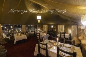 a restaurant with tables and chairs in a tent at Merzouga King Luxury Camp in Merzouga