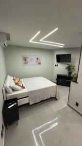 une chambre avec un lit et une télévision dans l'établissement Flats do Cabo e Suítes, à Arraial do Cabo