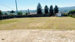 an empty field with a fence and a dirt road at Serene Guesthouse in Manzini