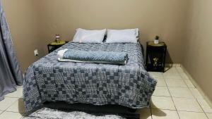 a bed in a bedroom with two night stands and two tables at Serene Guesthouse in Manzini +1 photo