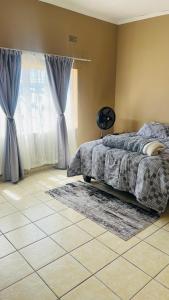 a bedroom with a bed and a window and a rug at Serene Guesthouse in Manzini