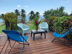 three chairs and a table on a wooden deck at Turquoise studio remarquable vue mer in Le Diamant
