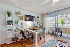 ein Wohnzimmer mit einem Schreibtisch, einem Tisch und Stühlen in der Unterkunft Salt & Palms at Plantation Hale E3 in Kapaa