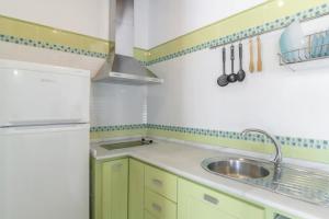 a small kitchen with green cabinets and a sink at Casas con piscina compartidas Garaje y Wi-Fi in Roche