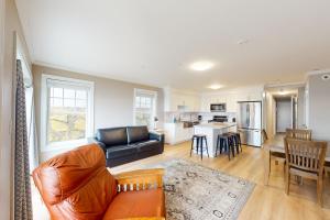 a living room with a leather couch and a kitchen at Summer Cape Escape in Dennis Port