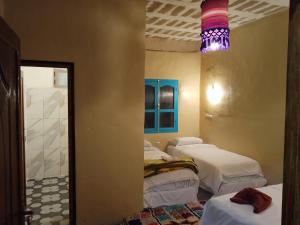 a room with three beds and a room with a mirror at Gîte Palma Eagle Ziz Canyon in Er Rachidia