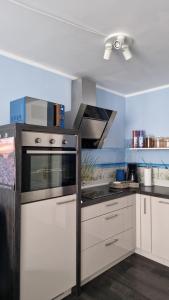 グラール・ミューリッツにあるOstseeeuleの白いキャビネットとコンロ付きオーブンを備えたキッチン