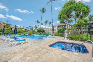 a pool with chaise lounge chairs and a swimming pool with palm trees at Pono Kai Resort D101 in Waipouli