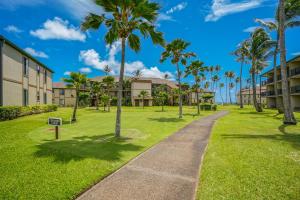 a walkway through a park with palm trees at Pono Kai Resort D101 in Waipouli