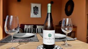 a bottle of wine sitting on a table with two glasses at Jacaranda stylish ambiance with volcano and ocean views in Tacoronte