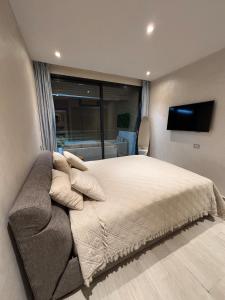 达布阿扎Appartement moderne avec vue mer & piscine, Dar Bouazza的一间配有大床和平板电视的卧室