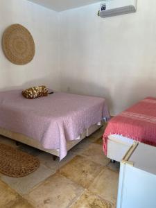 a room with two beds with purple sheets and a fan at Brisa Mansa in Barra Grande