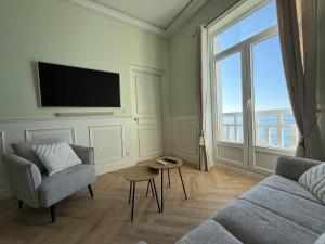 a living room with a couch and a tv at Vue Mer Panoramique - Appartement d'Exception in Wimereux