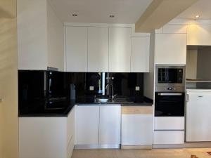 a kitchen with white cabinets and black counter tops at Gouveia Forest Guest House in Gouveia