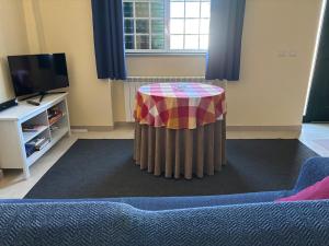 a living room with a table and a tv at Gouveia Forest Guest House in Gouveia